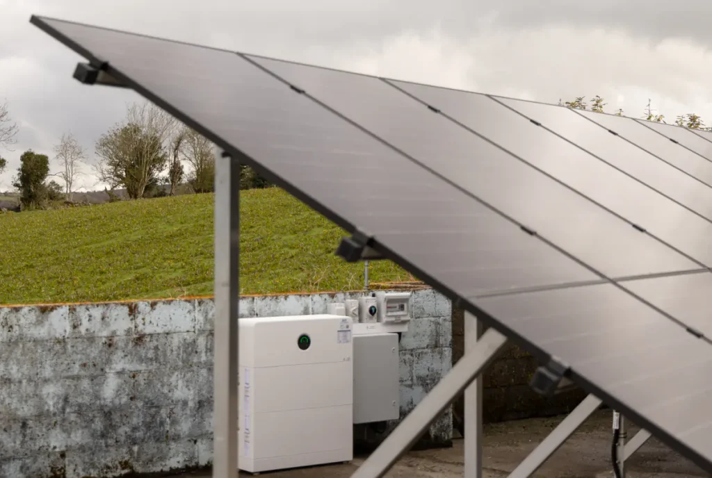 Ground-mounted solar panels with solar battery storage and electrical controls nearby.