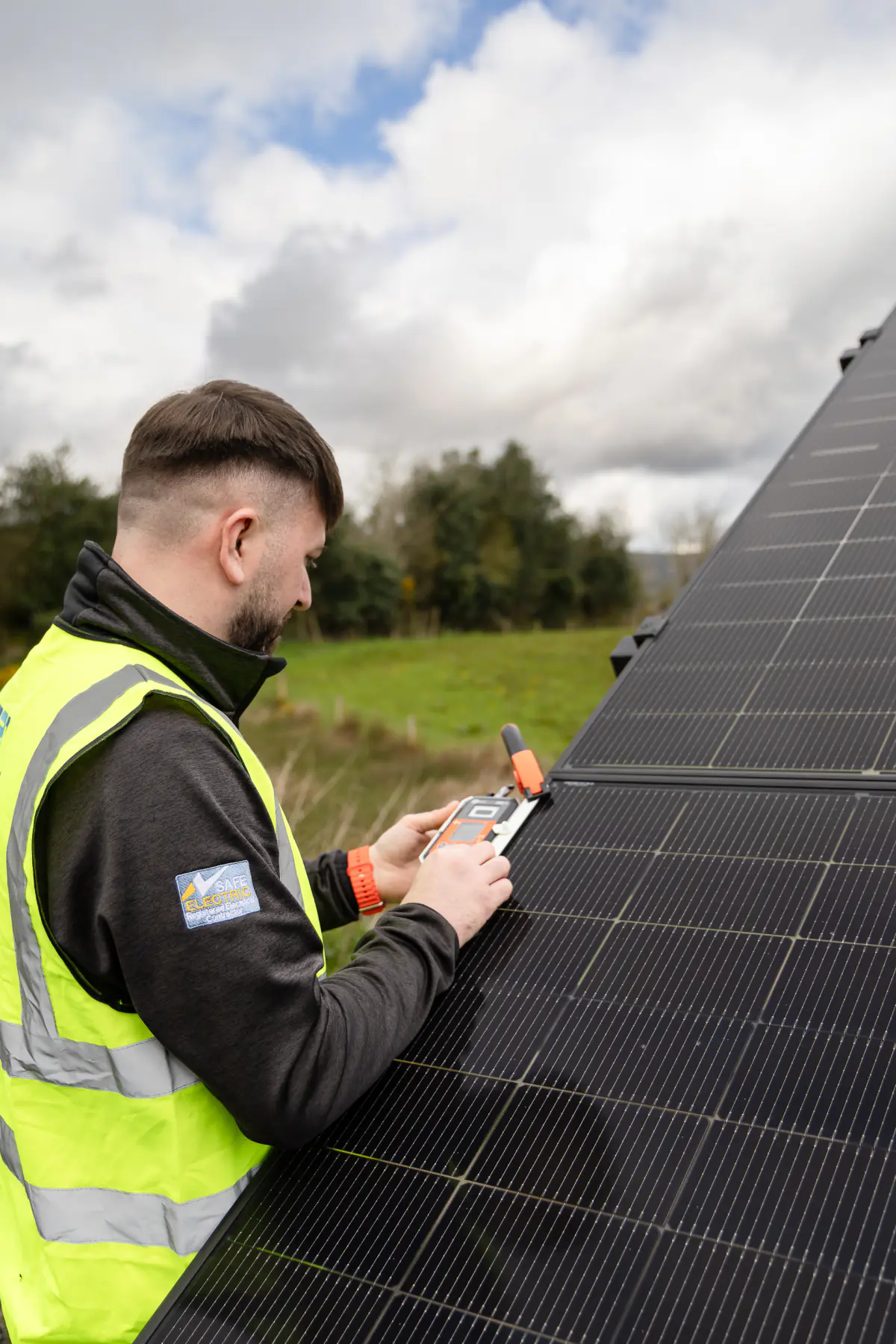 021 Electrician solar installer testing a ground-mounted solar panel in Cork.