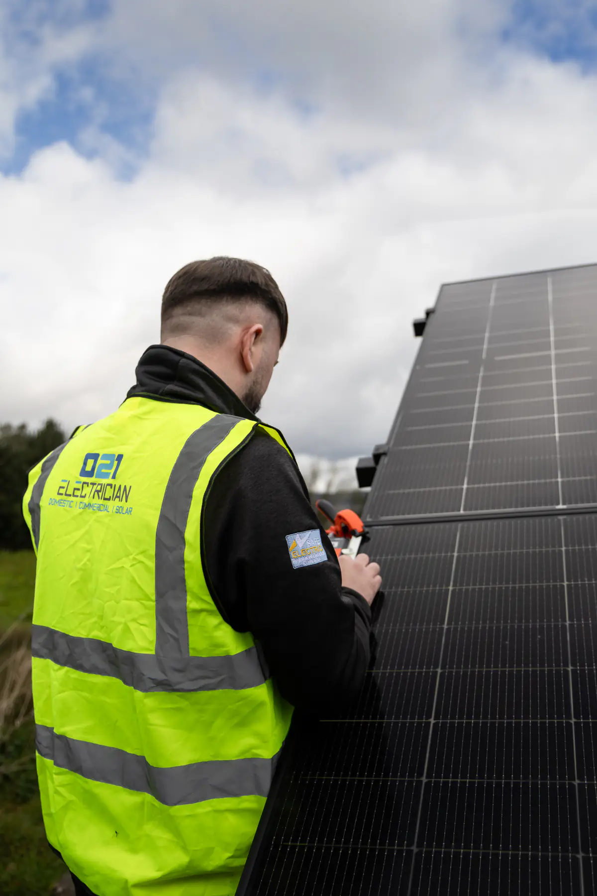 021 Electrician solar installer testing a ground-mounted solar panel in Cork.