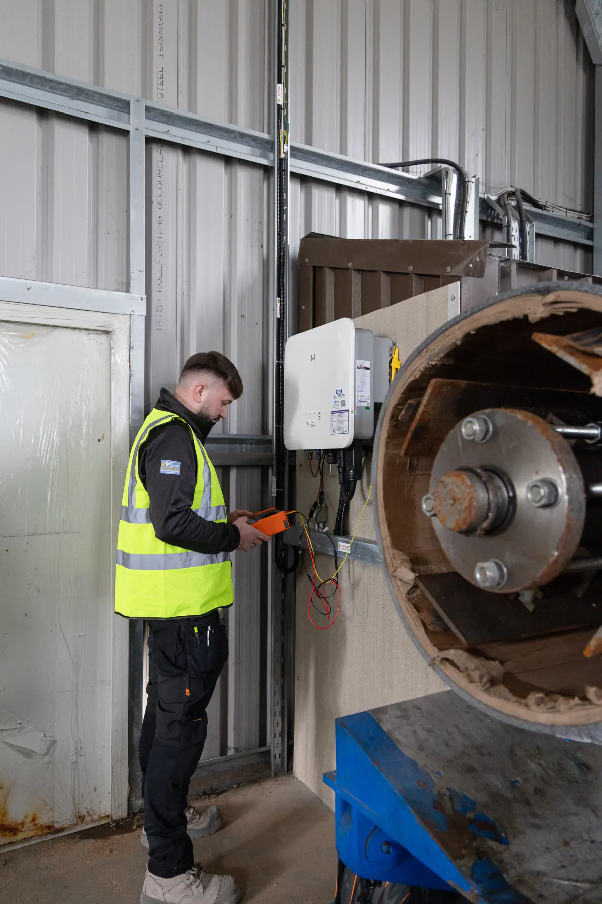 021 Electrician team member testing a commercial solar inverter inside an industrial building.