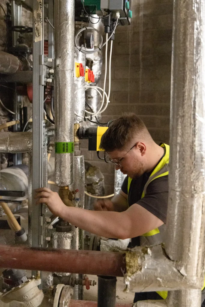 Electrician working on pipework and electrical systems inside a commercial plant room in Cork.