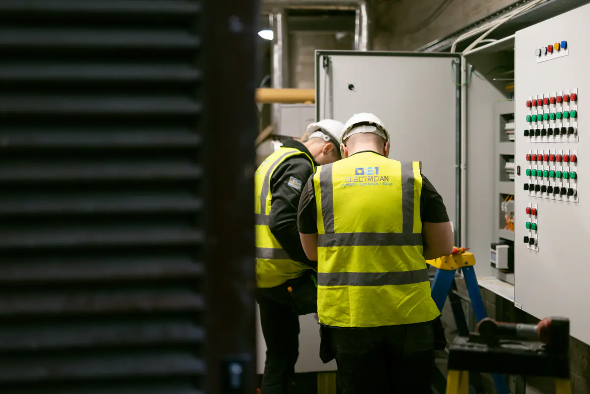 Two 021 Electrician team members working on a commercial electrical control panel in Cork.
