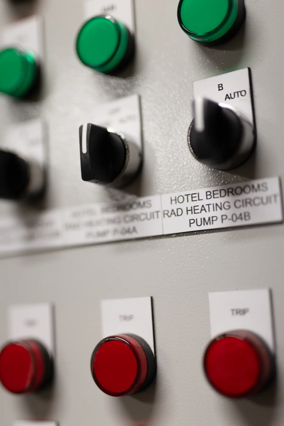 Close-up of commercial pump control switches labelled for hotel bedroom heating circuits.