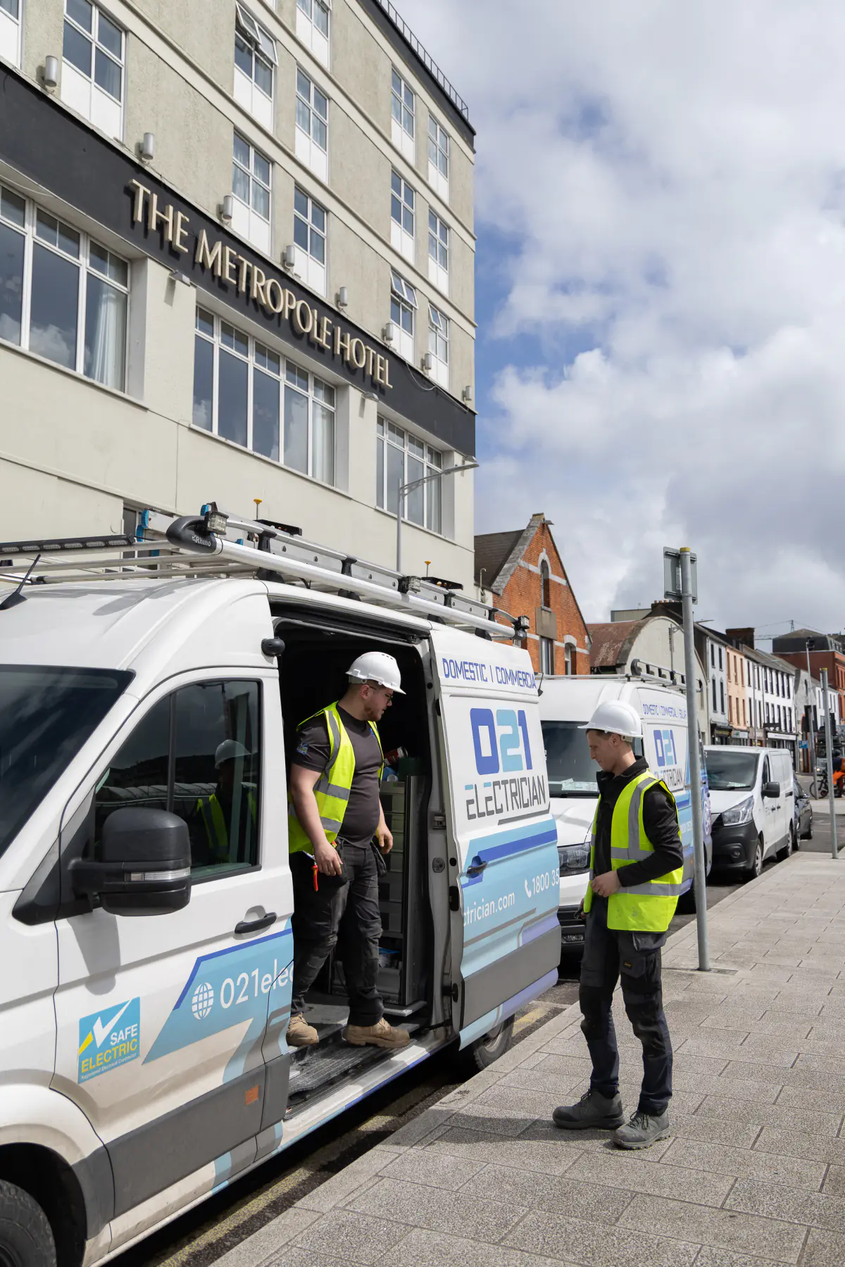021 Electrician team preparing tools from a branded van outside The Metropole Hotel Cork.